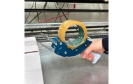 Dyspenser do taśmy pakowej Harmadon PushFlap 50 mm w trakcie zaklejania kartonu z taśmą PP, solidna konstrukcja i ergonomiczny uchwyt do pracy w magazynie i e commerce